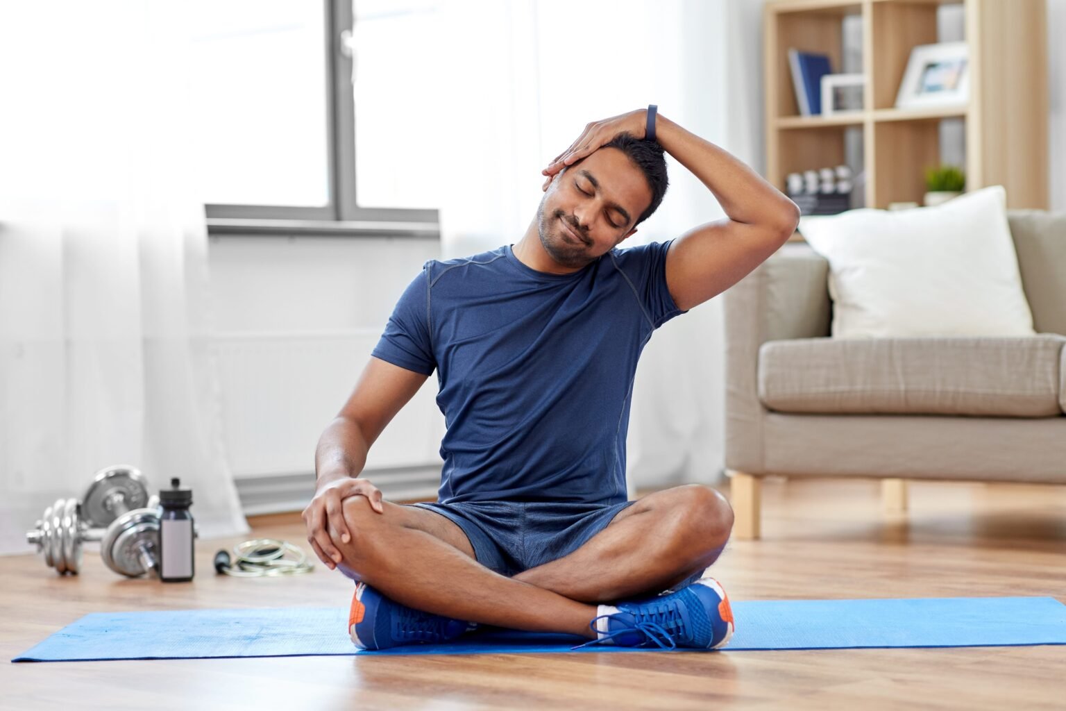 Simple Daily Habits That Can Help Reduce Neck Stiffness man-sitting-in-yoga-mat-with-arm-in-head-min