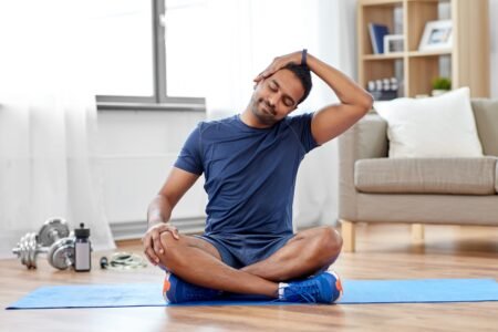 Simple Daily Habits That Can Help Reduce Neck Stiffness man-sitting-in-yoga-mat-with-arm-in-head-min
